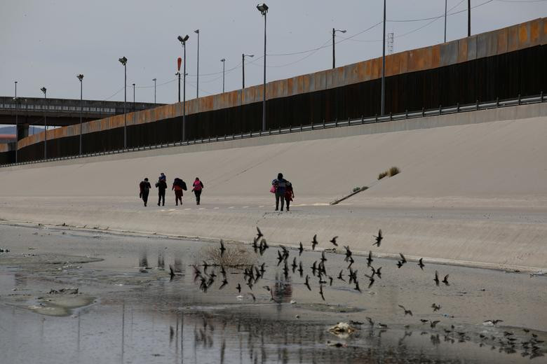 Các di dân đến từ Trung Mỹ đi cạnh hàng rào biên giới Mỹ-Mexico.