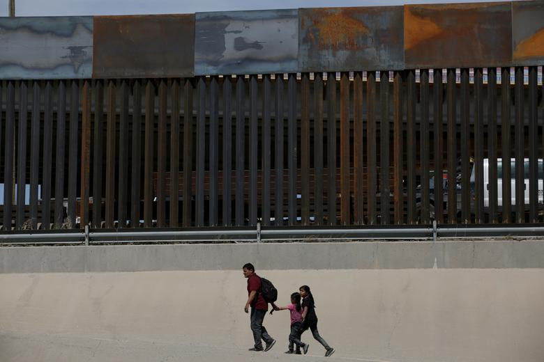 Người đàn ông đến từ Trung Mỹ dẫn theo hai con nhỏ vượt biên trái phép sang Mỹ để xin tị nạn tại El Paso, bang Texas, trong bức ảnh chụp từ Ciudad Juarez, Mexico, ngày 1/4.