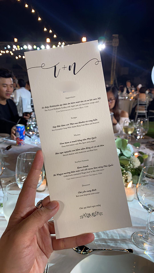  Thực đơn tiệc cưới Đông Nhi - Ông Cao Thắng lựa để đãi 500 khách mời gồm 7 món: sò điệp Hokkaido áp chảo ăn kèm mứt táo và sa lát cam Mỹ; súp hải sâm với thịt cua Alaska và rong biển; tôm hùm ủ muối hồng tiêu Phú Quốc; bào ngư nguyên con hầm nấm đông cô và cải thìa; kem chanh; bò Wagyu nướng thảo mộc với sốt rượu sim rừng Phú Quốc; chè Yến cung đình.