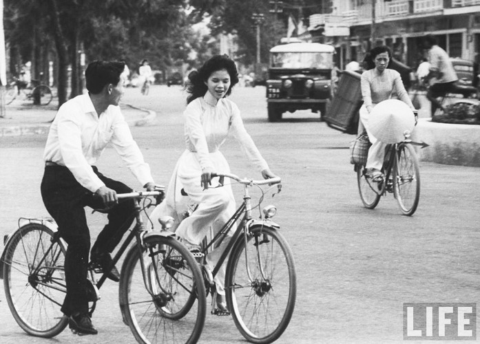 Cô gái mặc áo dài trò chuyện với một chàng trai khi đang đạp xe trên đường phố Huế năm 1961. Ảnh: John Dominis / Life.