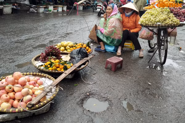 Những người phụ nữ bán hàng rong trên chợ Đồng Xuân ngồi sát vào nhau để tìm hơi ấm.
