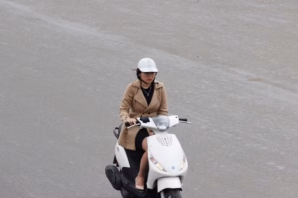 Cô gái co ro khi đi xe máy.