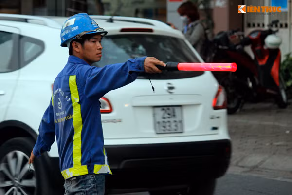 Một công nhân hướng dẫn các phương tiện di chuyển chậm và đi đúng làn đường của mình.