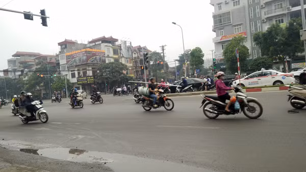 Một tay điều khiển xe máy, tay còn lại vác đồ vật trên vai phóng nhanh trên đường Tố Hữu (Hà Nội).