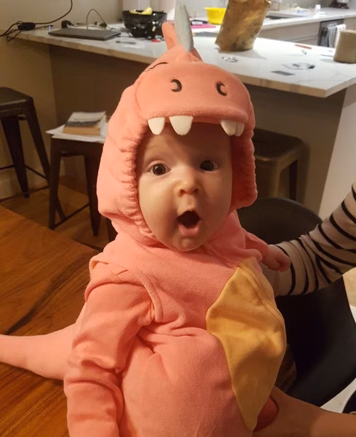 Em bé cực đáng yêu trong bộ đồ khủng long màu hồng.
