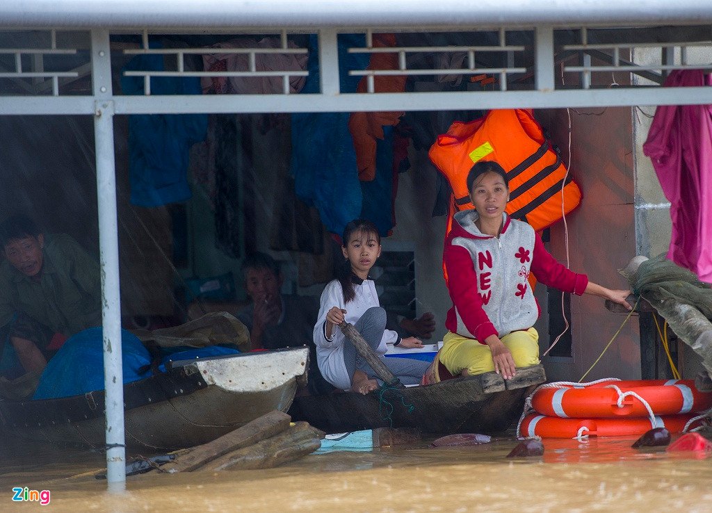 Nhà bị cô lập trong nước, người dân phải ngồi trên thuyền để tránh lũ.