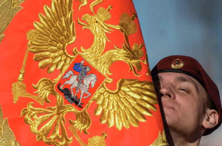 Người lính Nga dưới lá cờ có hình Quốc huy Liên Bang Nga.