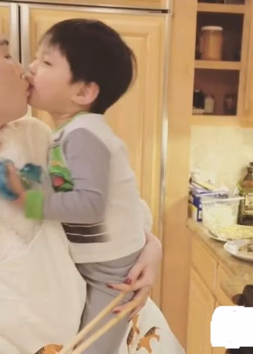 Theo đó, Ngọc Trinh một tay bế cháu trai của ông Hoàng Kiều một tay nấu ăn. Người đẹp còn âu yếm bón đồ ăn cho cậu bé. Ngọc Trinh cũng đã nhận được nụ hôn môi đầy ngọt ngào từ bé trai này. Có thể thấy, cô rất biết cách chiều chuộng và lấy lòng trẻ con. (Ảnh: Instagram Ngọc Trinh) 