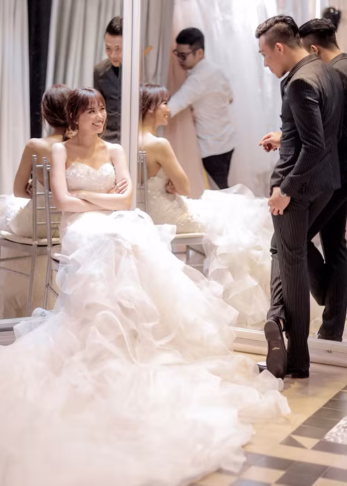 Mới đây, cặp đôi diễn viên phim “Bệnh viện ma” cũng đã đi thử trang phục cưới. Cả hai đã chọn các thiết kế của Chung Thanh Phong. Trong khi Trấn Thành sẽ diện hai bộ vest tông trắng thì Hari Won sẽ diện hai mẫu váy: một chiếc váy đuôi cá và một chiếc váy bồng bềnh. (Ảnh: Dân Việt) 