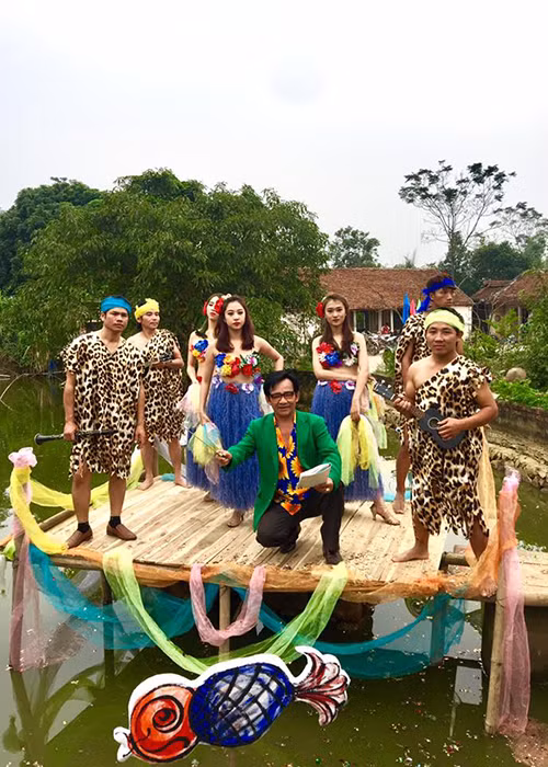 Nghệ sĩ Quang Tèo gây tò mò khi cầm đũa chỉ huy dàn nhạc bên cạnh các vũ công và nhạc công trong trang phục thổ dân. (Ảnh: Facebook nhân vật)