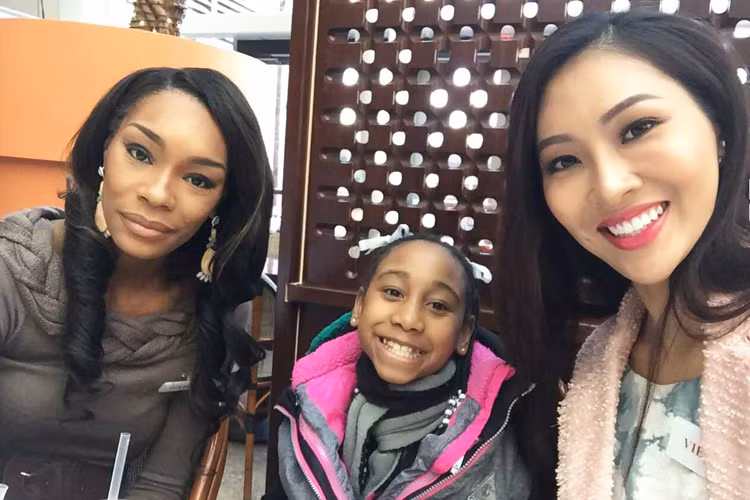 Hoa khôi Áo dài Việt Nam 2016 rạng rỡ chụp hình cùng một em nhỏ tại trung tâm. (Ảnh: Fanpage Miss World Vietnam)