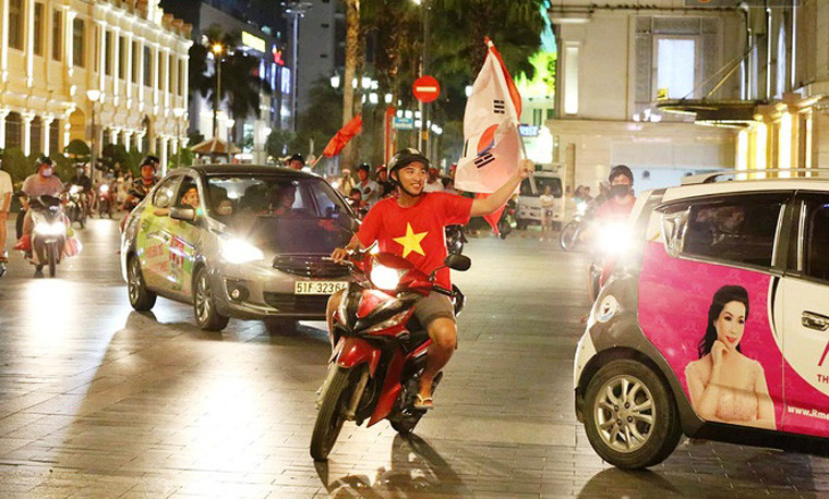 CĐV Việt Nam cầm cờ Hàn Quốc, quê hương của HLV Park Hang-seo xuống đường mừng chiến thắng.