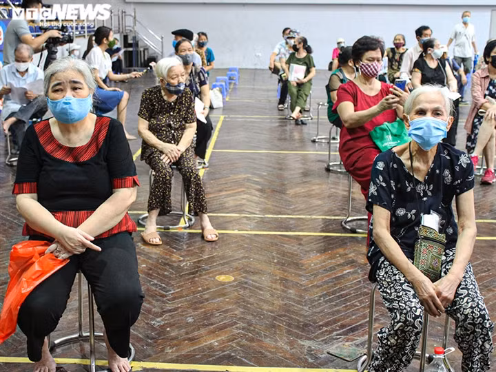 Phía bên trong Nhà thi đấu Trịnh Hoài Đức, người dân sau khi đo huyết áp, khám sàng lọc sẽ ngồi chờ đến lượt tiêm vaccine.