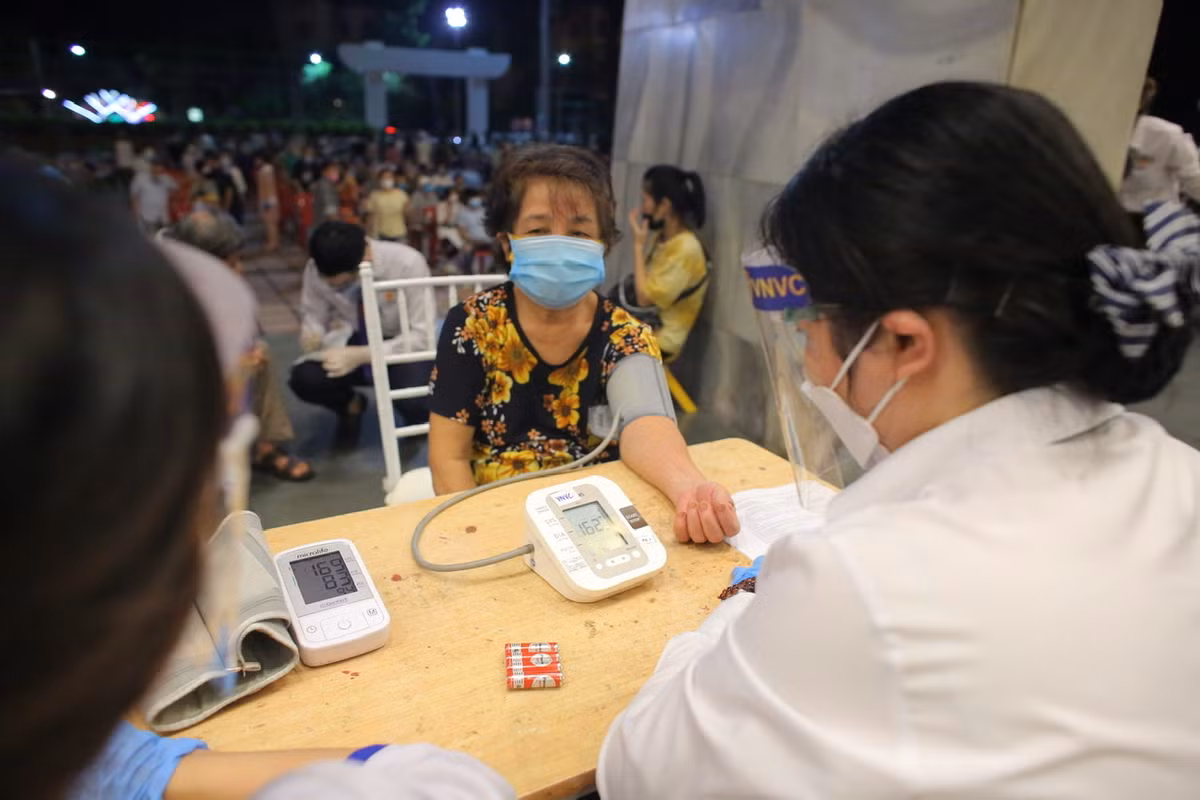 Những người đến tiêm được kiểm tra sức khoẻ trước khi vào tiêm.