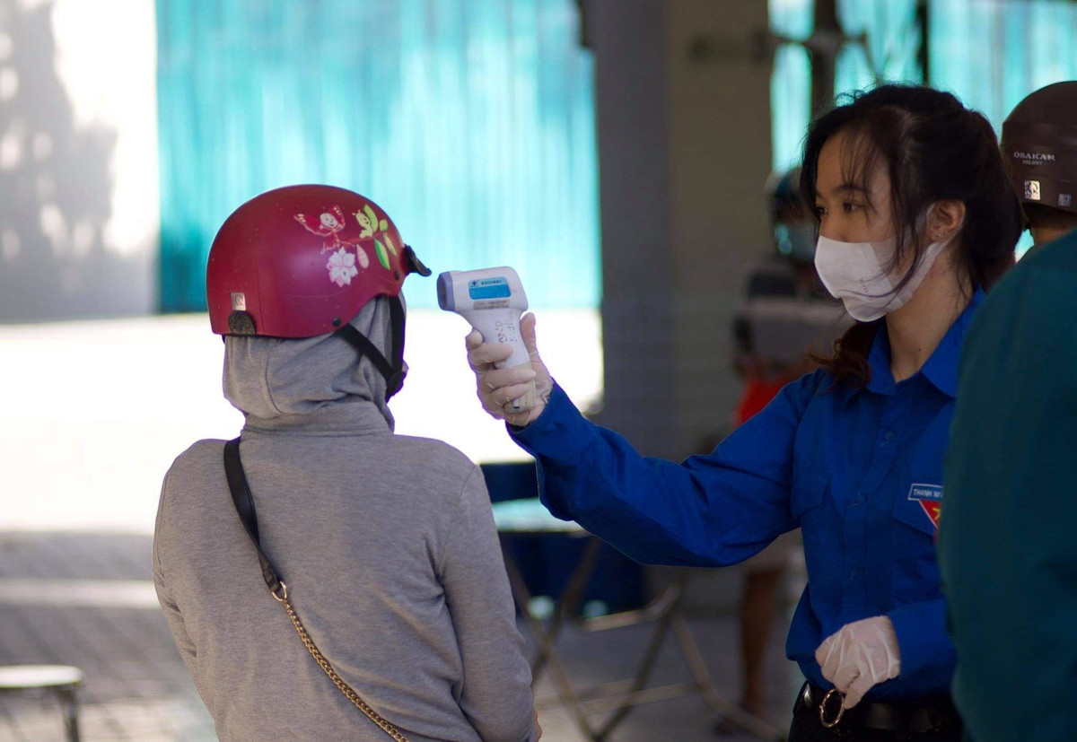 Mọi người đến mua bánh đều phải kiểm tra thân nhiệt. Có một số người đứng ngoài nắng nên nhiệt độ tăng cao sẽ được hướng dẫn ra đứng chỗ mát rồi chờ đo thân nhiệt lại.