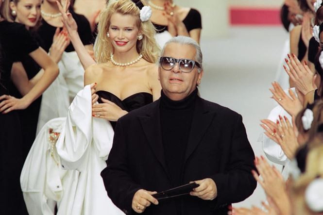 Giám đốc sáng tạo Chanel xuất hiện trên sàn catwalk cùng người mẫu Claudia Schiffer (đứng sau) và những chân dài khác sau khi kết thúc show Thời trang Thu - Đông năm 1995.