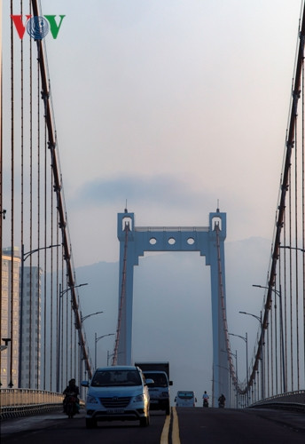 Nhiều người lưu thông trên cầu Thuận Phước bất ngờ trước làn sương mù. Phía xa là đỉnh núi Sơn Trà.