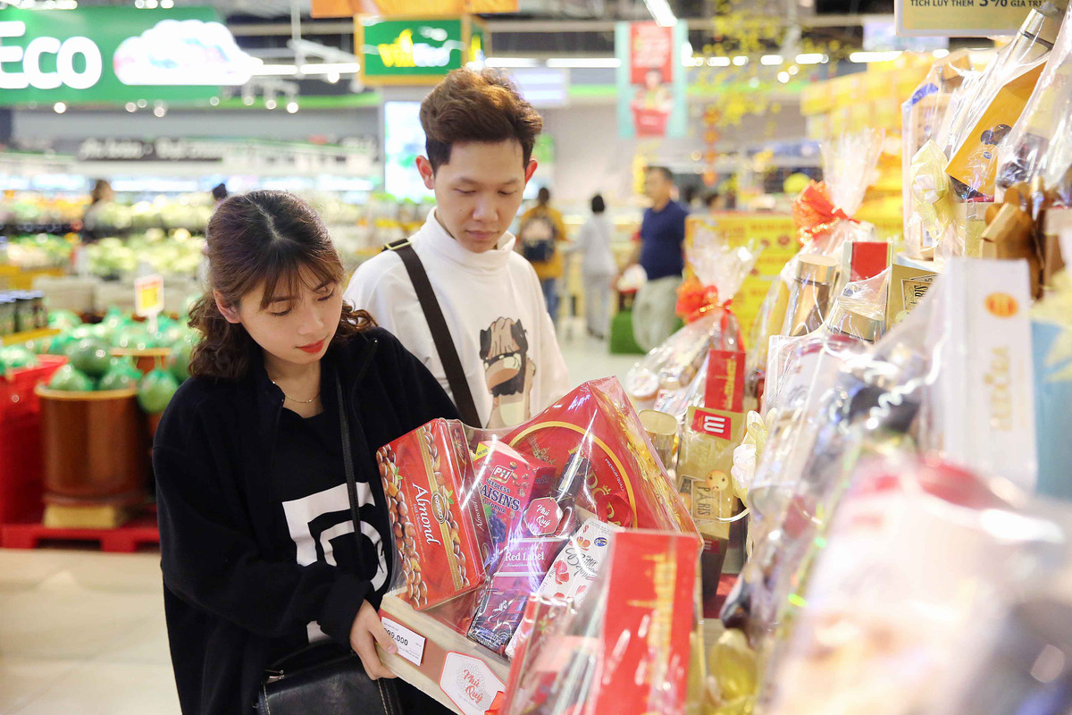 Một đôi vợ chồng trẻ đang lựa chọn giỏ quà Tết phù hợp để biếu gia đình nội ngoại 2 bên. Các loại giỏ quà Tết tại VinMart có giá từ bình dân 199.000 đồng đến cao cấp 2 triệu đồng phong phú chủng loại, từ giỏ quà bánh kẹo truyền thống cho đến các giỏ quà phong thuỷ độc đáo nên thu hút rất nhiều khách hàng.