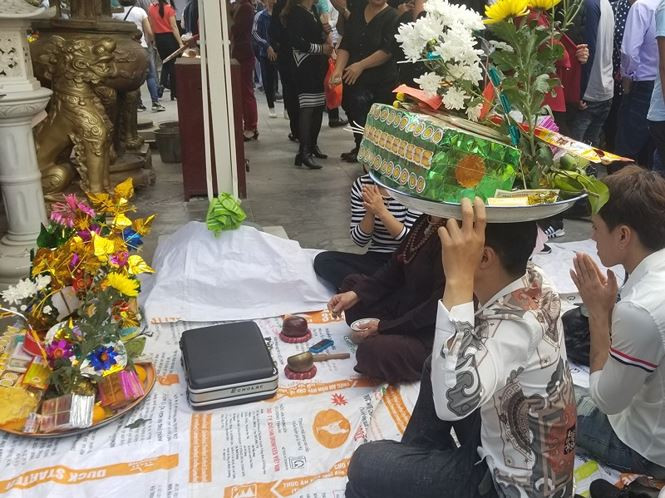 Một thanh niên đội mâm lễ trong khi cầu tài lộc tại sân đền.