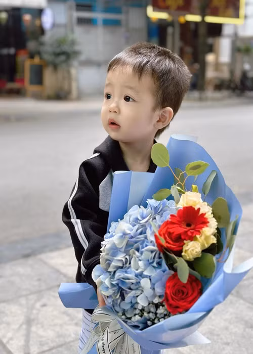 Bằng Kiều đăng tải hình ảnh con trai thứ tư ôm bó hoa, đồng thời viết: “Chúc toàn thể các bà, cô, chị, em ngày phụ nữ 8/3 tươi vui, khỏe đẹp ạ”.