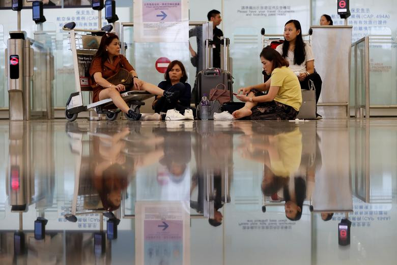 Cảnh sát đã sử dụng hơi cay, vòi rồng để trấn áp người biểu tình Hong Kong quá khích, trong khi đám đông ném gạch đá về phía lực lượng an ninh. Ảnh: Một số hành khách ngồi cạnh cổng an ninh bị đóng tại sân bay Hong Kong ngày 12/8.