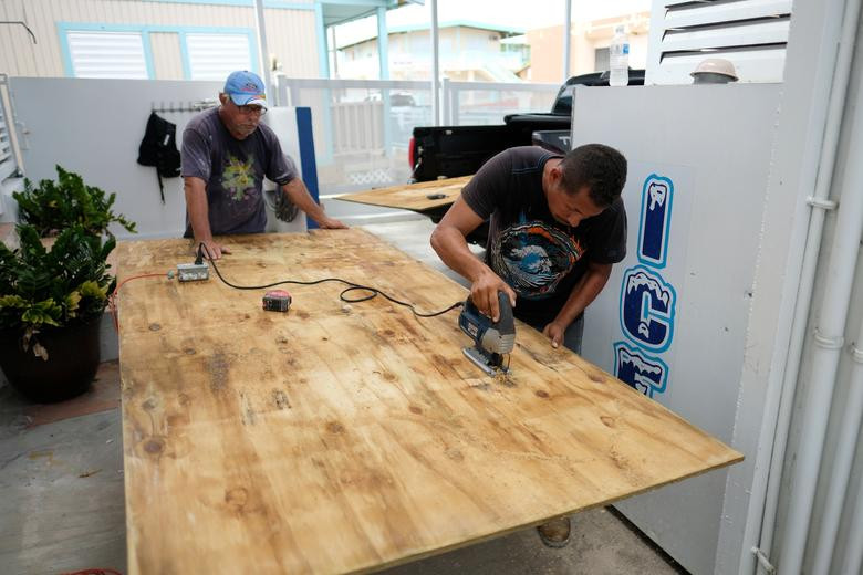 Mọi người chuẩn bị các tấm gỗ để che chắn cửa sổ cho một nhà hàng trên bãi biển ở khu du lịch El Combate, Cabo Rojo, ngày 27/8.