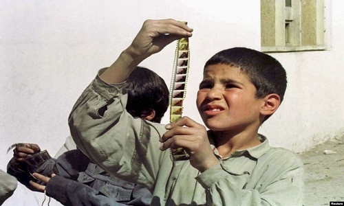 Bé trai nhìn cuộn phim đã bị phiến quân Taliban đem đi đốt trước đó.