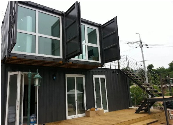 Ngôi nhà được chồng lớp các khối nhỏ container vuông vắn với nhau. Thang lên tầng 2 được bố trí bên ngoài. Cửa container được tận dụng thành lớp cửa ngoài cho cửa sổ.