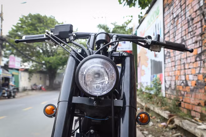 Đèn pha dạng tròn cổ điển sử dụng bóng halogen được thay mới, nhỏ gọn hơn so với đèn nguyên bản. Bên cạnh đó, đèn xi-nhan hình quả nhót cũng khiến đầu xe trở nên gọn gàng hơn, để lộ rõ phần phuộc ống lồng kích thước lớn.