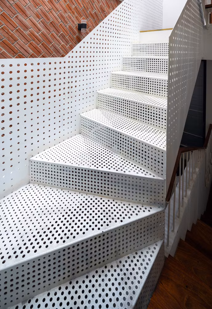 Chất liệu thép lỗ cùng bậc gỗ mở ở cầu thang tạo sự mới lạ đồng thời đảm bảo sự thông thoáng giữa các tầng.