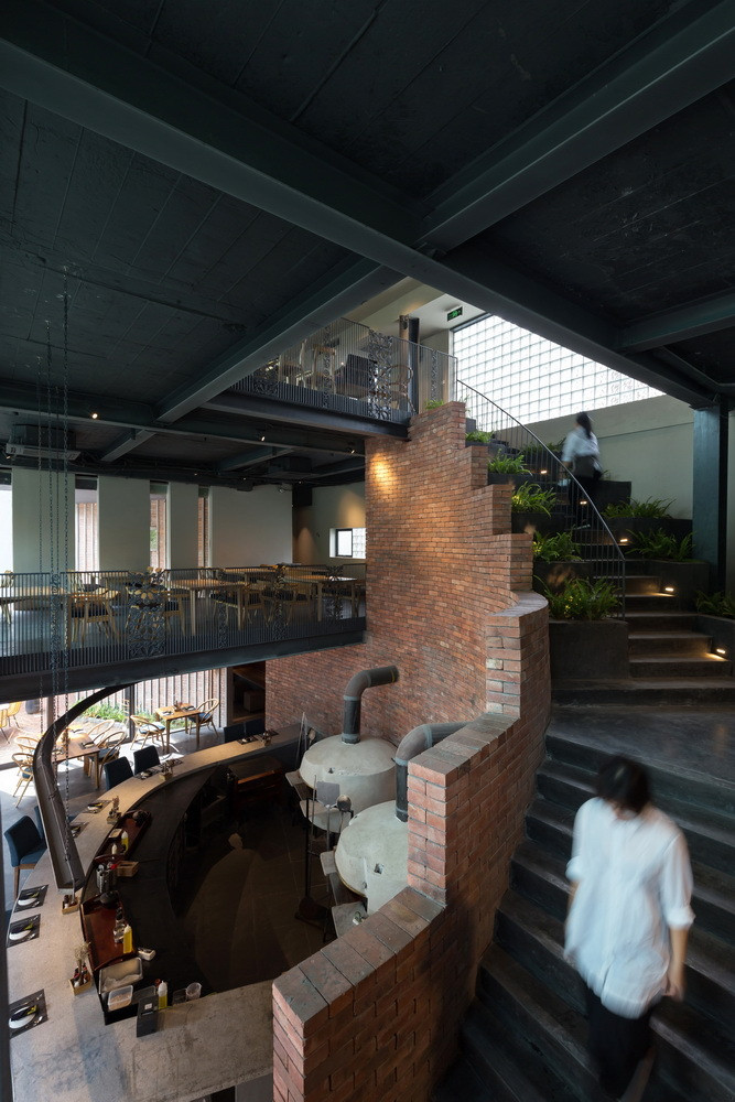 Bức tường gạch mộc tạo điểm nhấn trên nền đen xám của trần nhà phong cách công nghiệp.