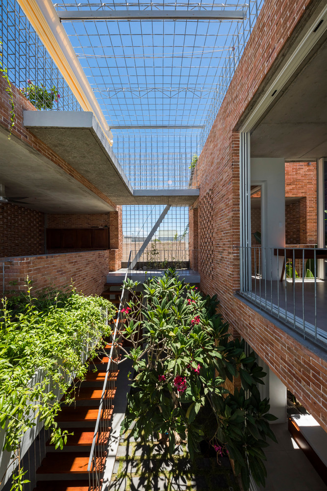 Không gian giữa nhà là sân vườn trồng các loại cây thân cao và cầu thang.