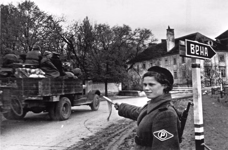 Trong ảnh là một cô giao liên trên tuyến đường dẫn vào thủ đô Vienna của Áo vào tháng 4/1945. Và những chữ “Vienna” trong tiếng Nga chỉ mang ký hiệu tượng trưng do đó rất cần tới lực lượng giao liên.