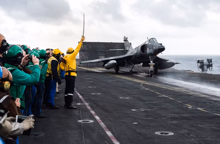 Hình ảnh sĩ quan chỉ huy bộ phận phóng máy bay trên tàu Charles de Gaulle dùng kiếm nghi lễ cho chuyến xuất kích cuối cùng của một chiếc Super Etendard.