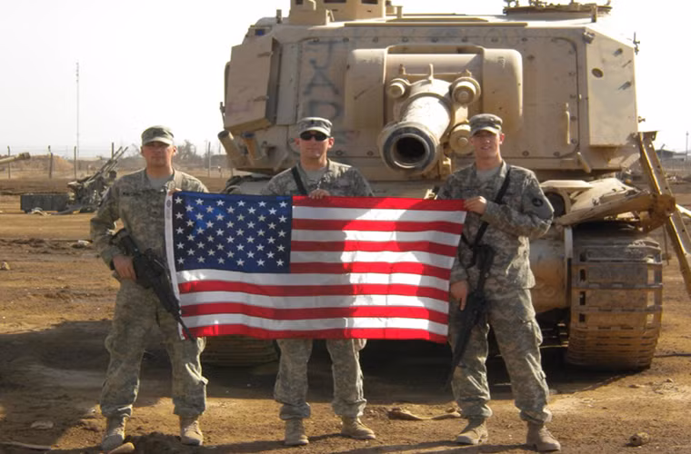 Từ năm 2003, quy mô của Taji ngày càng được mở rộng do tình trạng an ninh bất ổn tại Iraq sau khi Mỹ lật đổ chính quyền Saddam Hussein. Các thiết bị quân sự bị hư hỏng hoặc phá hủy trong giao tranh đều được chuyển đến Taji. Trong ảnh là một nhóm binh sĩ Mỹ chụp ảnh trước một khẩu pháo tự hành GCT 155mm bị bỏ lại Taji.