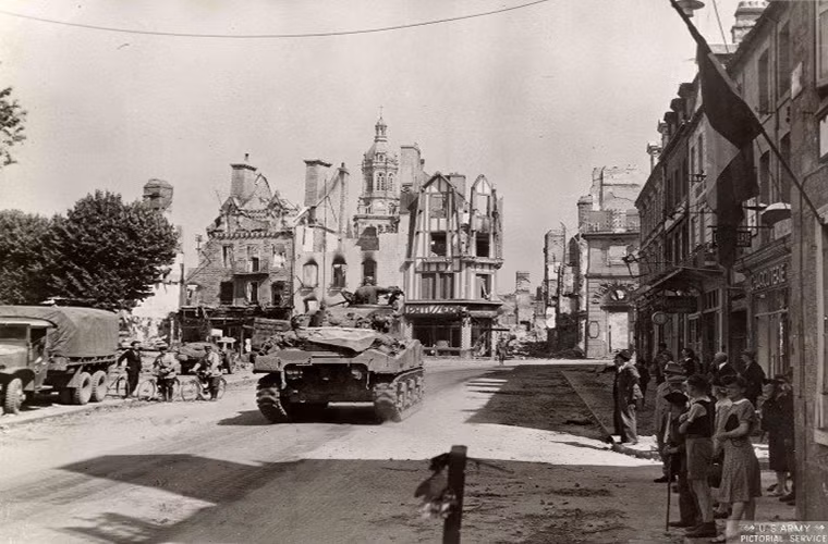Hình ảnh một chiếc xe tăng Sherman của Mỹ tiến vào một thị trấn ở Normandy sau bốn năm bị người Đức chiếm đóng từ năm 1940.