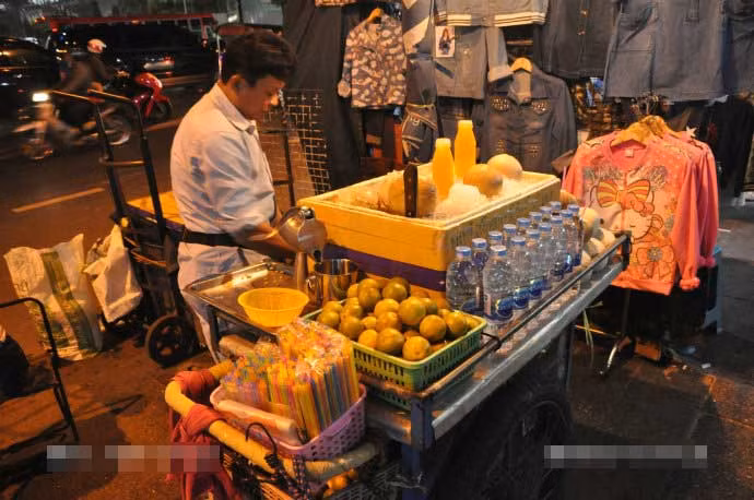 Anh bán hàng rong trên phố đêm Bangkok. Ảnh Sina