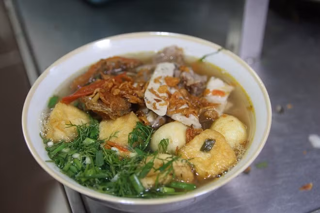 Miến chan thập cẩm thơm vị của cua, bùi và ngậy với cá rán, giòn giòn với giò tài ăn kèm với trứng cút, đậu rán chan nước dùng nóng hổi.