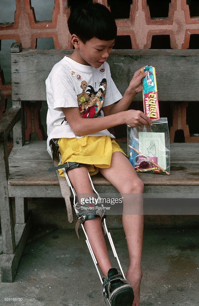 Cậu bé mồ côi bị bại liệt vui mừng với món quà vừa được tặng.