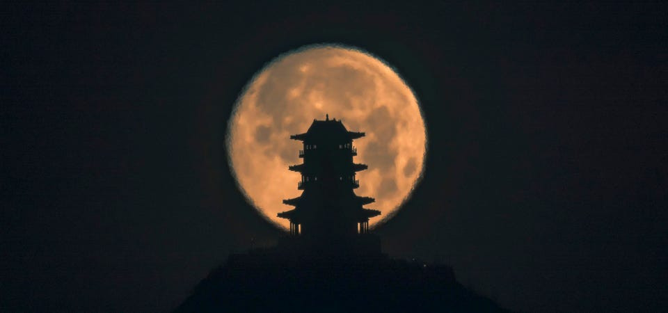 Mặt trăng lặn đằng sau tháp Dingdu Peak vào sáng sớm 17/1 ở Bắc Kinh, Trung Quốc.