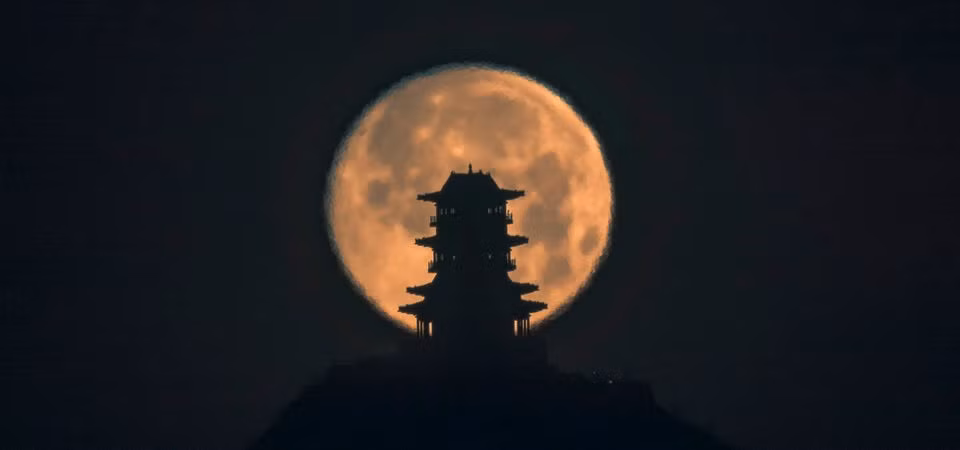 Mặt trăng lặn đằng sau tháp Dingdu Peak vào sáng sớm 17/1 ở Bắc Kinh, Trung Quốc.