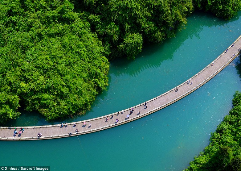 Cầu gỗ nổi ấn tượng nhìn từ trên cao. Đi qua cây cầu bắc qua dòng sông màu ngọc lam uốn lượn này, du khách có thể thưởng thức bức tranh phong cảnh tuyệt đẹp.