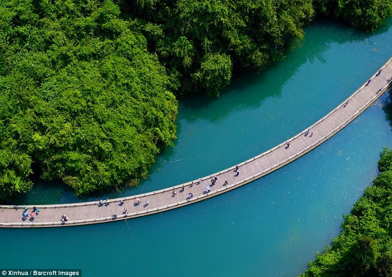 Cầu gỗ nổi ấn tượng nhìn từ trên cao. Đi qua cây cầu bắc qua dòng sông màu ngọc lam uốn lượn này, du khách có thể thưởng thức bức tranh phong cảnh tuyệt đẹp.