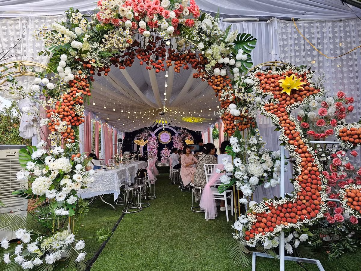 Bên cạnh hoa tươi, từng chùm vải thiều được kết thêm tạo thành điểm nhấn chuẩn "cây nhà lá vườn" trong đám cưới này.