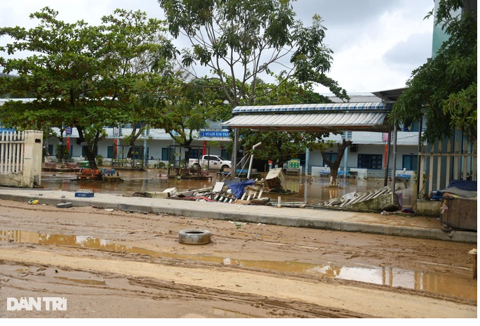 Một đoạn bờ tường của trường tiểu học Hồng Quang bị nước lũ giật sập. Trong sân trường ngổn ngang bùn đất (Ảnh: Quốc Triều).