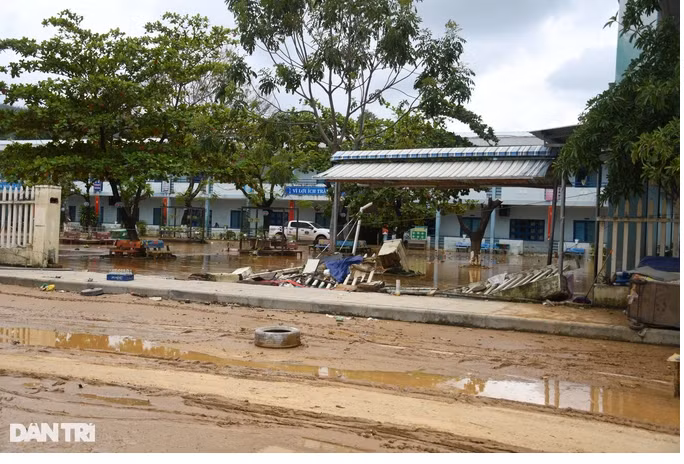 Một đoạn bờ tường của trường tiểu học Hồng Quang bị nước lũ giật sập. Trong sân trường ngổn ngang bùn đất (Ảnh: Quốc Triều).