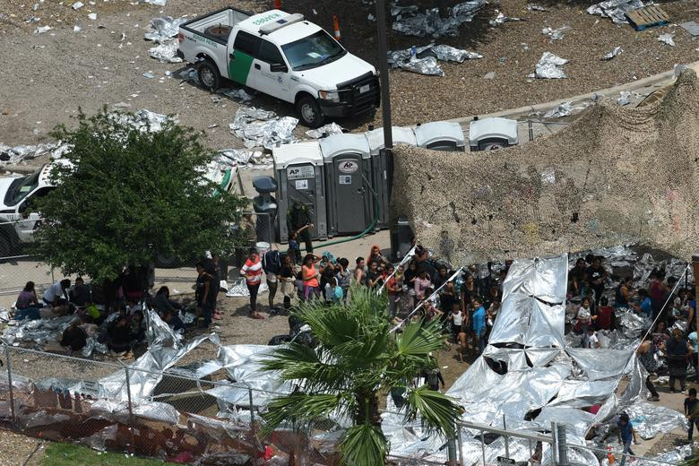 Những người dân di cư đứng chen chúc nhau trong khu trại tạm bợ.