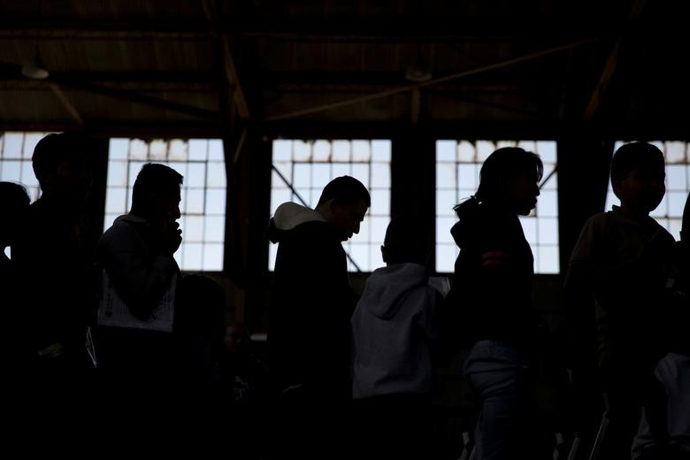 Những người nhập cư xếp hàng chờ được đưa từ khu tiếp nhận sang nơi ở tạm thời trong Khu hội chợ Tây Nam New Mexico.