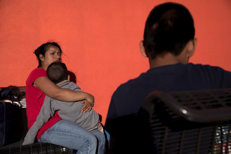 Cô Serne Gutierrez ngồi ôm con trong lúc chờ xe buýt để được đưa tới nơi ở tạm thời.