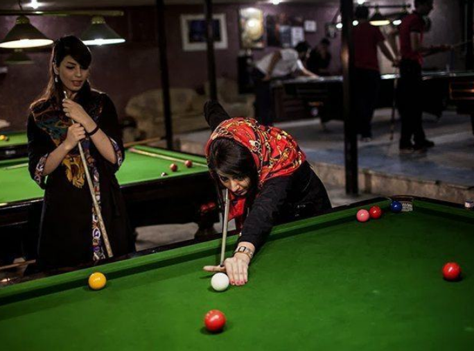 Hai người phụ nữ chơi bi-a tại một điểm giải trí.